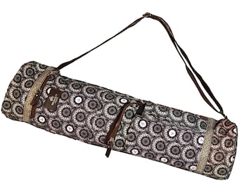 May include: A black and white patterned yoga mat bag with a brown adjustable shoulder strap. The bag has a zippered pocket on the side and a zippered closure at the top.