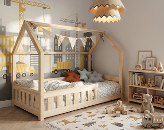 Könnte beinhalten: Kinderzimmer mit einem holzhausförmigen Bett, einem Teppich mit Hirsch- und Baummustern und einem Holzregal. Die Wände sind mit einem Wandbild zum Thema Bau dekoriert. Eine Holz-Pendelleuchte hängt von der Decke.