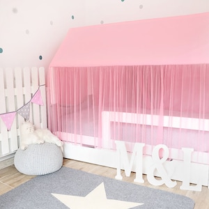 Puede incluir: Una cama con dosel rosa con un marco blanco y un caj&oacute;n blanco con las letras "M & L" en la parte delantera. La cama est&aacute; decorada con un dosel de tul rosa y una valla blanca con una pancarta gris y rosa.