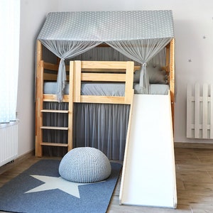 May include: A wooden loft bed with a slide and a gray and white star patterned canopy. The bed has a ladder and a gray and white star patterned rug underneath.