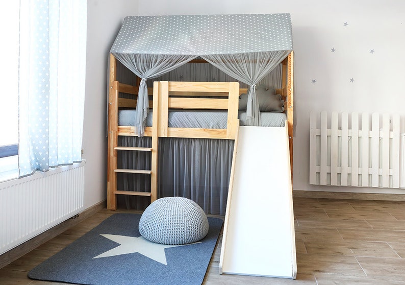 May include: A wooden loft bed with a slide and a gray and white star patterned canopy. The bed has a ladder and a gray and white star patterned rug underneath.