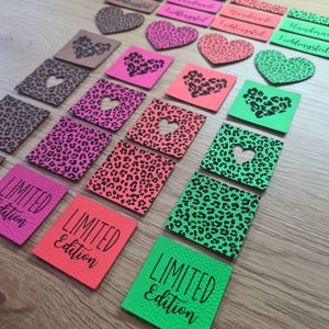 May include: A collection of colorful, textured leather patches and heart-shaped embellishments. The patches feature leopard print patterns and heart cutouts, with some displaying "LIMITED Edition" text. Colors include pink, green, and orange.