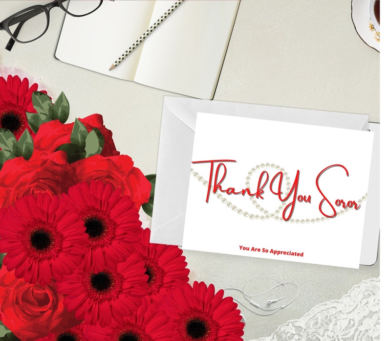May include: A white greeting card with the words "Thank You Soror" in red script, with a pearl design. The card is next to a white envelope and a bouquet of red flowers, including roses and gerbera daisies.
