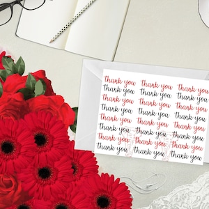 May include: A white envelope containing a sheet of paper printed with the words "thank you" in red and black script. The image also features a bouquet of vibrant red flowers, a notebook, and a pair of glasses.