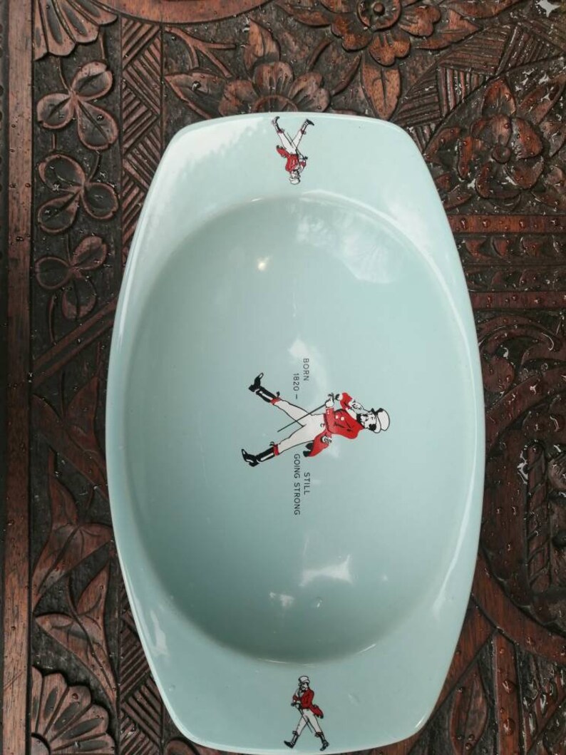 May include: A light blue ceramic ashtray with a walking man graphic and the text "Still Going Strong - 1920 -  "