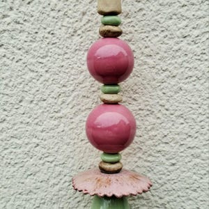Op de afbeelding: Een decoratieve tuinpaal met een gelaagd ontwerp. Het heeft een bordeauxrode punt, twee roze bollen en een groene, druppelvormige basis. De paal is ongeveer 30 cm hoog.