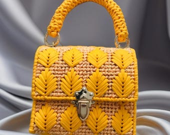 May include: A small, yellow handbag with a woven design featuring leaf-like patterns. The bag has a matching yellow handle and a silver clasp. The background is a soft, gray fabric.