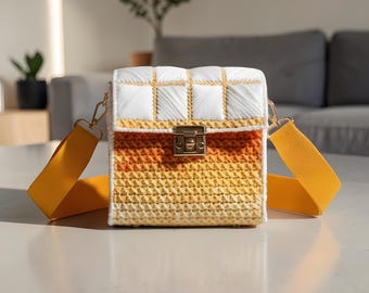 May include: A square, handmade crossbody bag with a white and yellow gradient design. The bag features a gold clasp and a wide, yellow shoulder strap. The top section is white with a grid pattern.