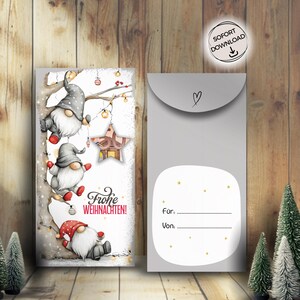 Puede incluir: Juego de tarjetas y sobres con temática navideña. La tarjeta presenta tres gnomos con sombreros grises y barbas blancas, con las palabras "Frohe Weihnachten!". El sobre es gris con un corazón y espacio para nombres.