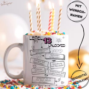Könnte beinhalten: Eine weiße Keramik-Tasse mit dem Text "LEVEL 13 UNLOCKED" und verschiedenen humorvollen Phrasen. Die Tasse ist mit einem kuchenartigen Design, bunten Streuseln und brennenden Kerzen bedeckt. Die Tasse ist beidseitig bedruckt.