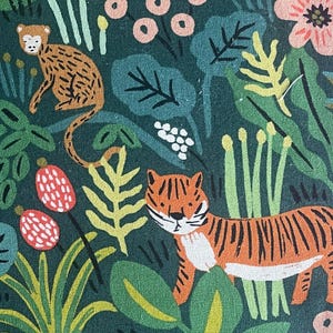May include: A dark green fabric featuring a repeating pattern of jungle animals including a tiger, a leopard, and a red bird. The design includes various botanical elements such as light green leaves, pink flowers, and small red berries throughout.