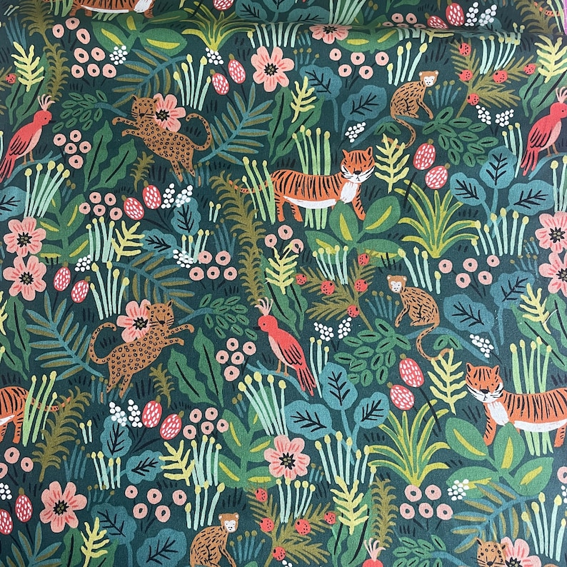 May include: A dark green fabric featuring a repeating pattern of tigers, leopards, monkeys, and pink birds amidst lush foliage, including various green leaves, stems, and small pink and white flowers scattered throughout the dense jungle design.
