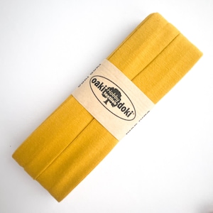Nahaufnahme eines 5m langen Jersey-Schrägbandes aus elastischem Stoff in ockergelb.