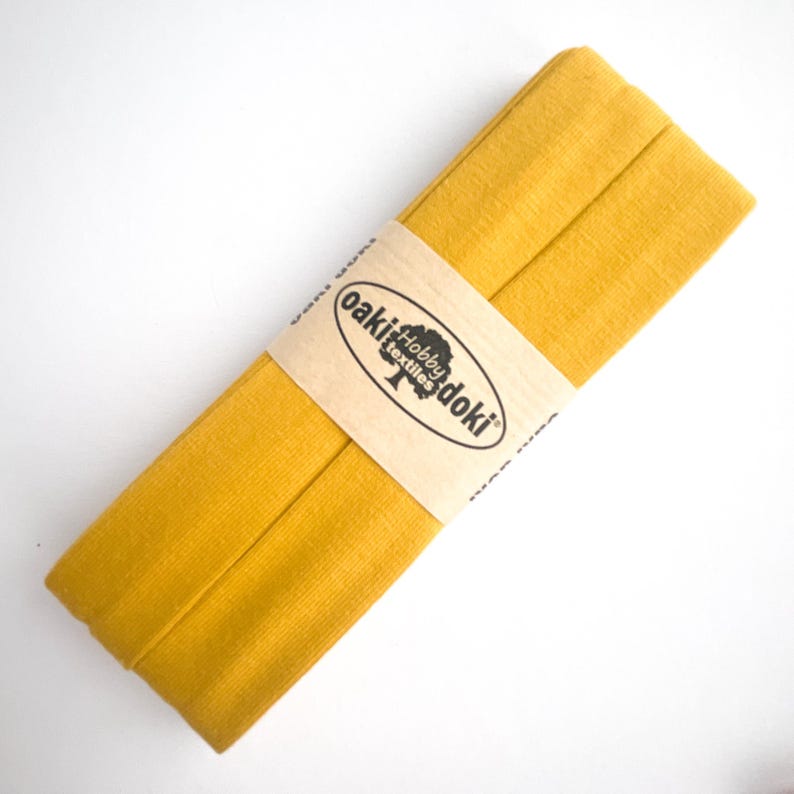 Nahaufnahme eines 5m langen Jersey-Schrägbandes aus elastischem Stoff in ockergelb.