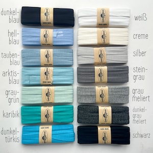 May include: Fourteen folded fabric strips arranged in two columns, each secured with a tan paper band labeled oaki doki. The colors include dark blue, light blue, dove blue, arctic blue, gray-green, Caribbean, turquoise, white, cream, silver, stone gray, heather gray, dark heather gray, and black.