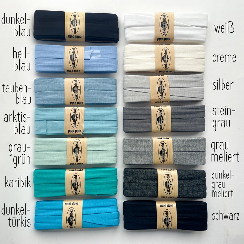 May include: Fourteen folded fabric strips arranged in two columns, each secured with a tan paper band labeled oaki doki. The colors include dark blue, light blue, dove blue, arctic blue, gray-green, Caribbean, turquoise, white, cream, silver, stone gray, heather gray, dark heather gray, and black.