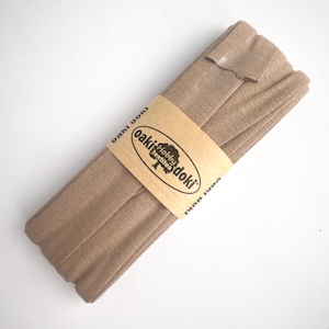 Nahaufnahme eines 5m langen Jersey-Schrägbandes aus elastischem Stoff in beige.