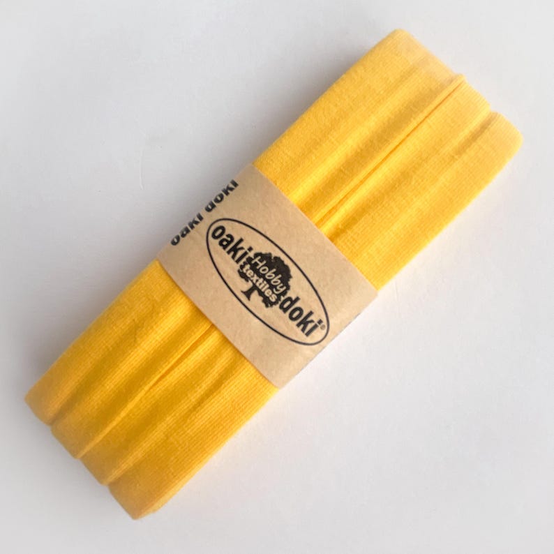 Nahaufnahme eines 5m langen Jersey-Schrägbandes aus elastischem Stoff in gelb.