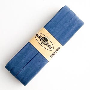 May include: A folded strip of dark blue fabric bias tape wrapped in a tan paper band. The paper band features the black printed text Oaki Doki Hobby Textiles and the Oaki Doki logo. The fabric has a visible woven texture and a matte finish.