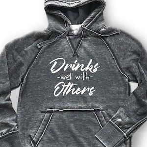 May include: A gray hooded sweatshirt with a distressed look. The text "Drinks -well with- Others" is printed in white on the front.