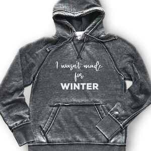May include: A gray hooded sweatshirt with a distressed look. The text "I wasn't made for WINTER" is printed in white on the front.