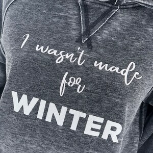 May include: A gray hooded sweatshirt with the text "I wasn't made for WINTER" printed in white.