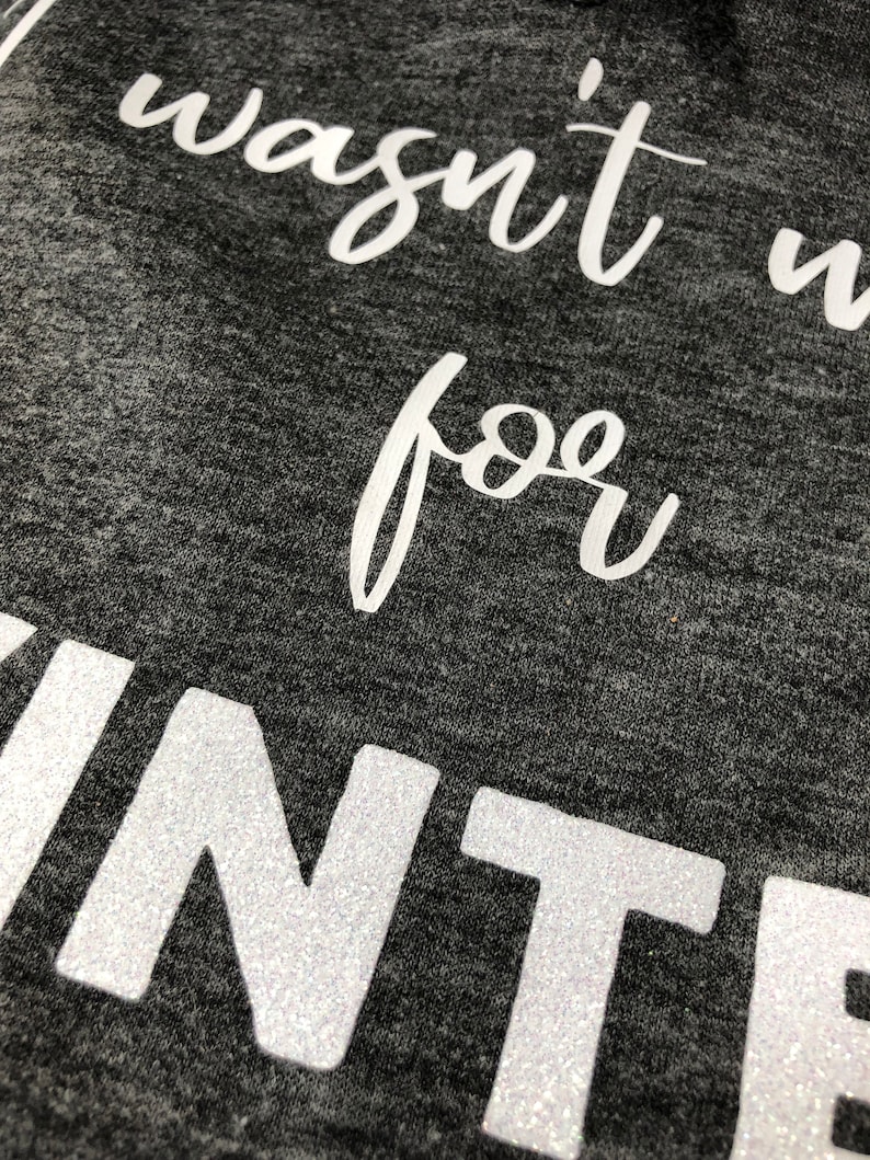 May include: Close-up of a gray shirt with white glitter lettering that reads "wasn't made for winter".