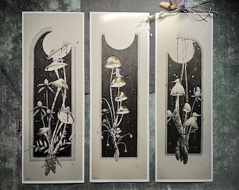 May include: Three black and white illustrations of mushrooms with gold accents. The mushrooms are depicted in a stylized art deco style with intricate details. The illustrations are framed in a black and white border.
