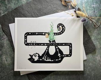 May include: A black and white art print featuring a cat skeleton holding a green potion bottle. The cat is upside down, with a bone-shaped frame around it. The potion bottle has green bubbles rising from it. The art print is on a white background.