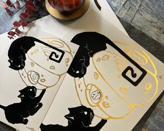 May include: Two black cat silhouettes are printed on white card stock. Each cat is holding a gold foil cheese wheel with the number "2" printed on it. The cheese wheels are outlined in black.