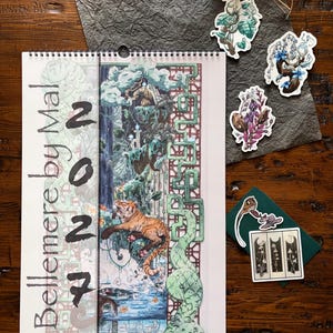 May include: A spiral-bound wall calendar titled Bellemere by Mal 2024 featuring a detailed illustration of a tiger in a lush forest setting with a green geometric border. Several small die-cut stickers of plants and mushrooms are placed nearby.