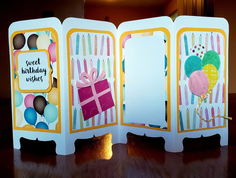 May include: A white card with a four-panel screen design. Each panel has a different birthday-themed design. The first panel has a balloon pattern with the text "sweet birthday wishes". The second panel has a pattern of colorful candles. The third panel is blank. The fourth panel has a pattern of colorful candles with a pink gift box and a cluster of balloons.
