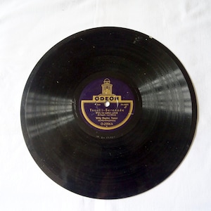 May include: A vintage black vinyl record with the label "ODEON" in gold and purple. The label features the text "Toselli-Serenade" and "Willy Beyler, Tenor". The record is on a white background.