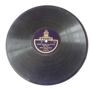 May include: A black vinyl record with a purple and gold label. The label features the word "ODEON" and German text. This vintage record is a classic music format, likely from the mid-20th century.