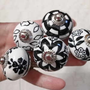 May include: Five ceramic drawer knobs with black and white floral patterns. Each knob has a silver metal base.