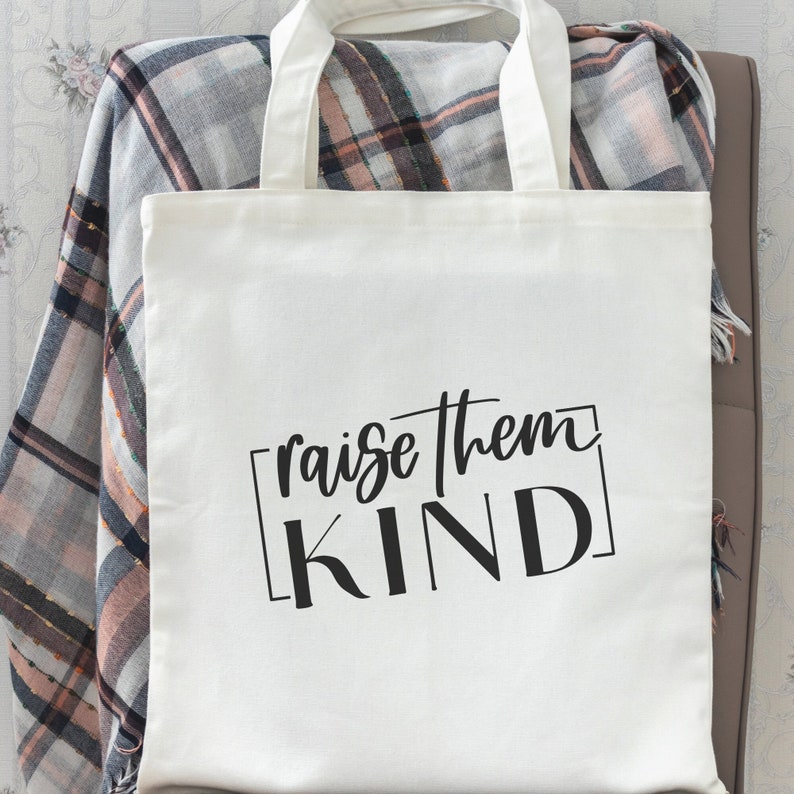 May include: White canvas tote bag with black text that reads "raise them KIND" in a square frame.