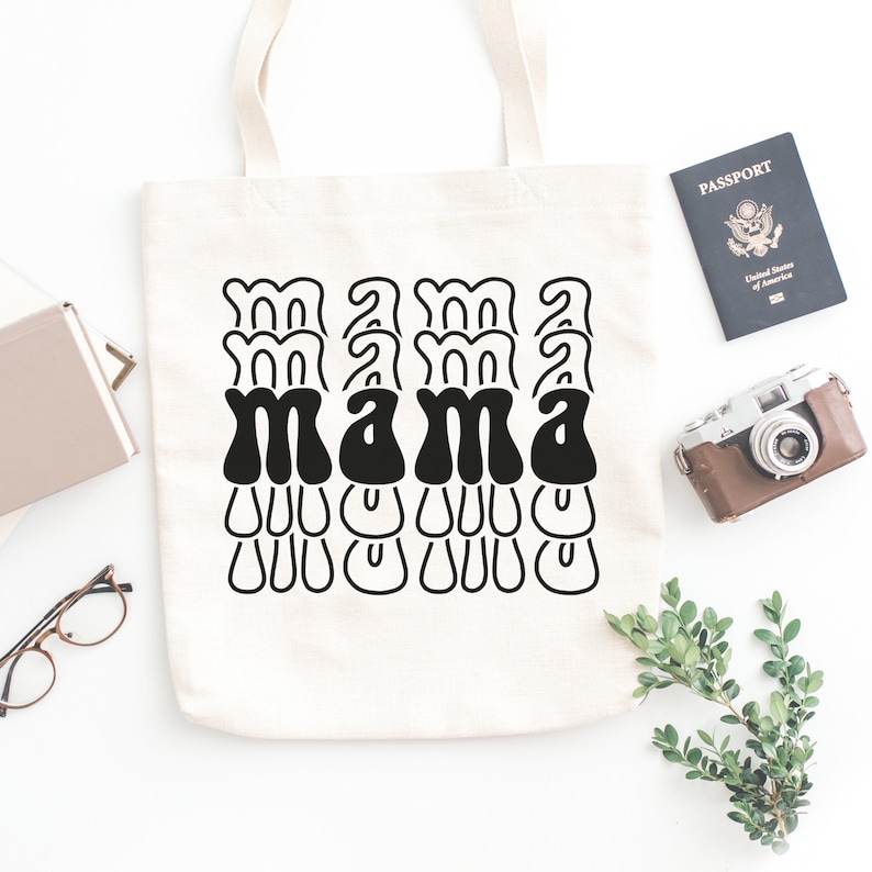 May include: A white canvas tote bag with black text that reads "mama" in a retro font. The text is repeated multiple times in a layered design.
