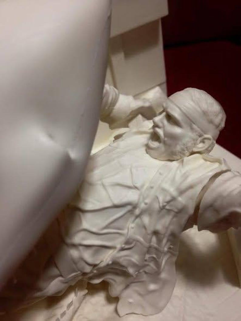 May include: A white sculpture of a person in a distressed pose, with a bandage on their head and an open mouth. The sculpture has detailed textures and is set against a neutral background.