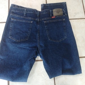 May include: A pair of dark blue denim jeans with a Wrangler label on the back pocket.