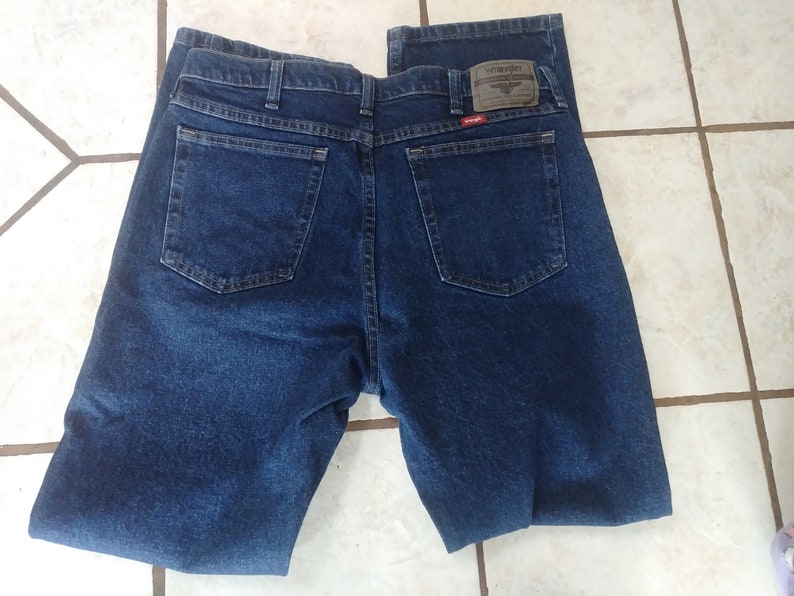 May include: A pair of dark blue denim jeans with a Wrangler label on the back pocket.