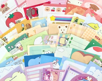 May include: A large collection of colorful memo pads and sticky notes featuring various cartoon characters, animals, food items, and patterns. The stationery set includes diverse shapes, pastel and bright color palettes, and printed text like Memo.