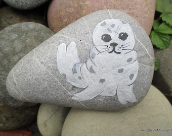 Small seal on the beach, painted stones, stone art, beach landscape on stone,