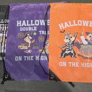 May include: Three drawstring bags in black, purple, and orange, each with Halloween-themed graphics and text. The bags show cartoon characters in costumes, with the text "HALLOWEEN ON THE HIGH SEAS" and "ON THE HIGH" printed on them.