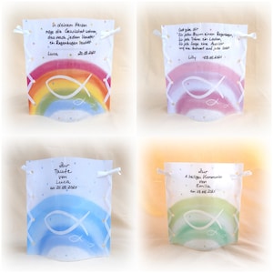 Könnte beinhalten: Vier bunte Regenbogenkarten mit einem weißen Fischsymbol und Text. Die Karten sind mit weißen Bändern und goldenem Glitzer verziert. Der Text auf den Karten lautet: "In deinem Herzen moge die Gewissheit wohnen, dass nach jedem Unwetter ein Regenbogen leuchtet Luca 20.08.2010", "Gott gebe dir fur jeden Sturm einen Regenbogen, fur jede Tranc ein Lachen, fur jede Sorge eine Aussicht und eine Antwort auf jedu boleh Lilly 09.06.2021", "Zur Taute von Luca am 20.08.2020", und "Zur A heiligen Kommunion von Emilia am 08.06.2021".