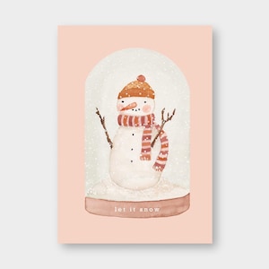 Könnte beinhalten: Eine Aquarell-Illustration eines Schneemanns in einer Schneekugel mit einem braunen Hut und einem rot-weiß gestreiften Schal. Die Schneekugel steht auf einem braunen Sockel mit dem Text "let it snow" darauf.