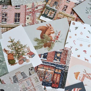 Könnte beinhalten: Eine Sammlung von Weihnachtskarten mit verschiedenen Aquarellillustrationen. Designs umfassen einen Pinguin, Hasen mit einem Weihnachtsbaum, ein Eichhörnchen und ein Reh. Einige Karten haben Text, darunter "merry christmas" und "Wunderbare Weihnachten."
