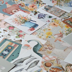 K&ouml;nnte beinhalten: Eine Sammlung bunter Karten mit verschiedenen Designs, darunter ein Kassettenband, eine Gie&szlig;kanne mit Blumen, ein Vogel, eine Gans und ein Geb&auml;ude mit der Aufschrift "BOOKSHOP".