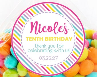 May include: A clear cellophane bag filled with colorful candies, tied with a pink polka dot ribbon. A round sticker on the bag reads "Nicole's Tenth Birthday" with the date 03.22.27. The sticker has a striped design in various colors.