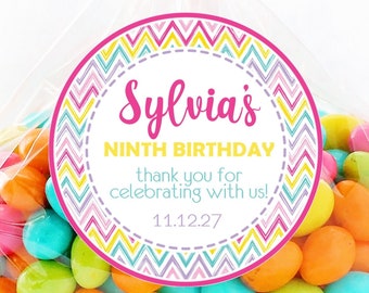 May include: A clear cellophane bag filled with colorful candies, tied with a pink polka dot ribbon. A round sticker on the bag reads "Sylvia's NINTH BIRTHDAY" with the date 11.12.27. The sticker has a pink and yellow chevron design.