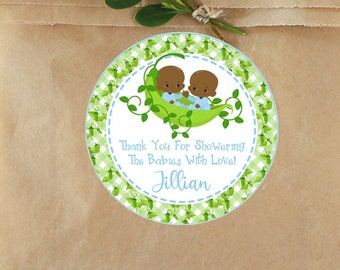 May include: A brown paper bag with a round sticker featuring two cartoon babies in a pea pod. The sticker has a green and white gingham border and text that reads "Thank You For Showering The Babies With Love! Jillian."
